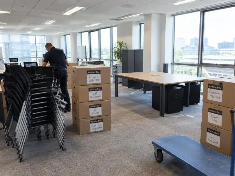 Stacked chairs and labelled archive boxes during an office move