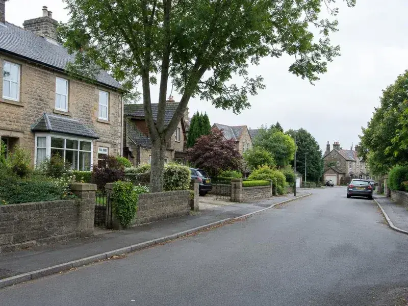 Tree-lined residential street of stone houses in West Yorkshire